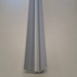 End view of a silver metal V-shaped extrusion resting on a pale surface.
