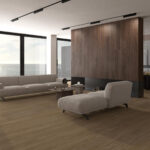 Open-concept living room with beige sectional sofa, chaise lounge, and a wood-paneled divider, overlooking an ocean view.