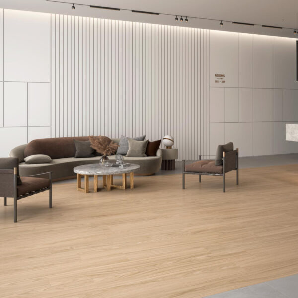 Contemporary lounge area with a curved gray sofa, two chairs, and a round marble coffee table on a light wood floor against white paneled walls.