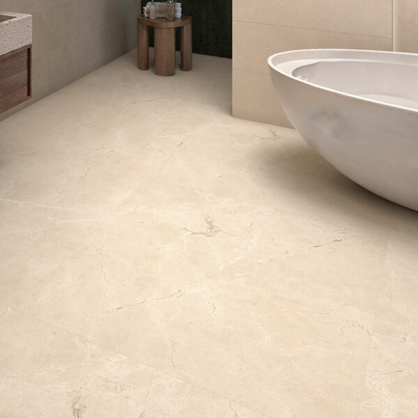 Beige marble bathroom floor with a white freestanding tub along the wall and a small wooden stool with toiletries in the corner