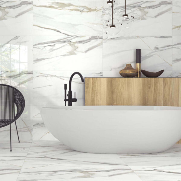 Freestanding white bathtub with black faucet beside a wooden vanity in a marble-tiled bathroom. (informative)