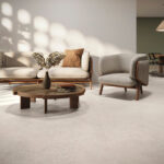 Neutral living room scene: beige sofa and matching armchair around a round wooden coffee table, vase of dried flowers, and soft natural light.