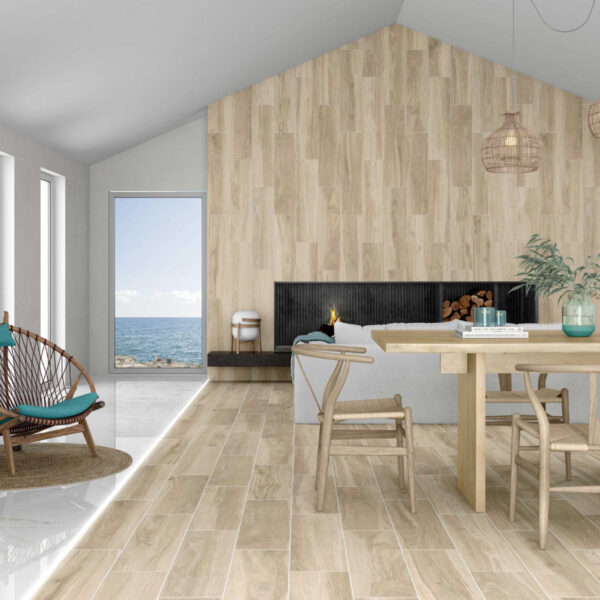 Bright coastal living room with a tall wood-paneled wall, a built-in fireplace, and a wooden dining table; large window shows the sea outside.