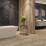 Modern bathroom showroom with white freestanding tub, wooden pillar, and black marble walls with white veining.