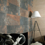 Slate-tiled wall in gray and rust tones with a white tripod floor lamp nearby.
