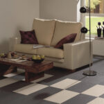 Beige sofa with burgundy pillows in a bright living room; wooden coffee table with apples and cups.
