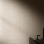 Beige textured wall with a dark modern faucet visible at the sink in the lower right corner.
