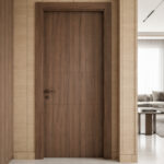 Dark wood interior door set in a light wood-paneled hallway, with a living room and sofa visible through the right doorway behind a partial wall.