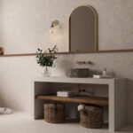 Contemporary bathroom with a concrete vanity, stone basin sink, arched mirror, hex tile backsplash, and a vase of greenery.