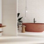 Modern bathroom with a terracotta freestanding bathtub, white textured tile wall, black faucet, and a potted plant.
