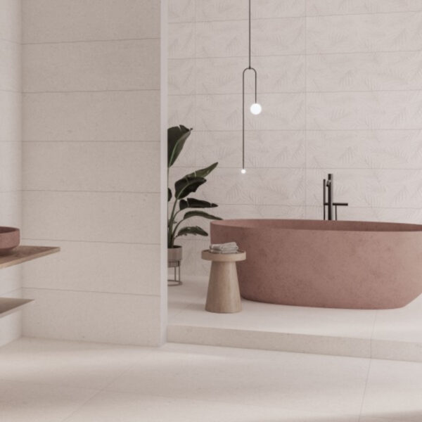 Modern bathroom scene featuring a pink freestanding bathtub, black faucet, hanging pendant lights, and a small wooden stool with towels beside a potted plant.