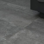 Gray tiled floor with the bottom edge of a dark sofa or cabinet visible in the upper-right corner.