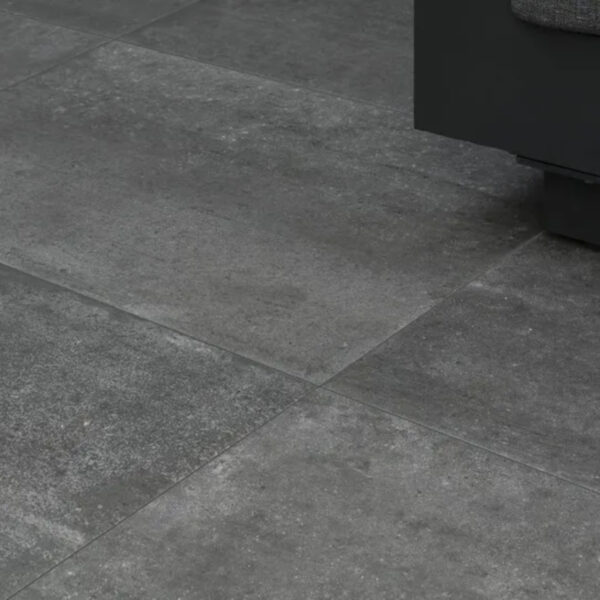 Gray tiled floor with the bottom edge of a dark sofa or cabinet visible in the upper-right corner.